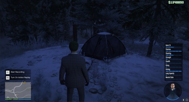 A GTA Online character, with green hair and a blue suit, standing in front of a navy tent with blood on it.