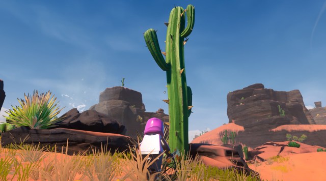 A LEGO Fortnite player standing in front of a green cactus in a desert.