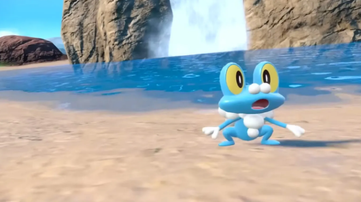 Froakie standing in front of a waterfall in the Coastal Biome in the Pokémon Scarlet and Violet DLC.