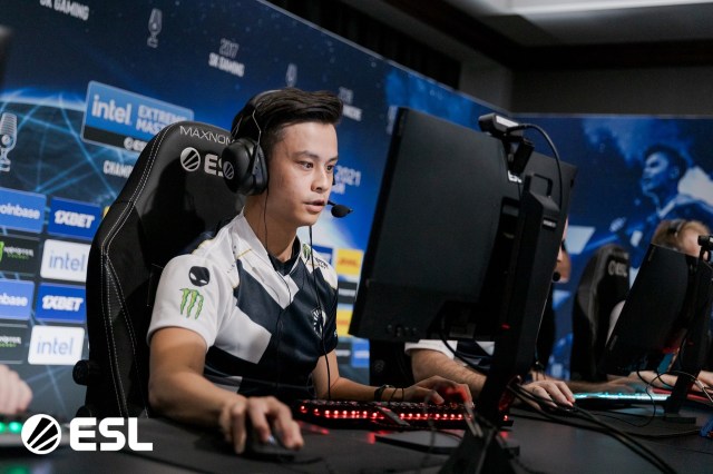 Stewie2K sitting at a computer screen, with his hand on a mouse, wearing a navy and white Team Liquid jersey.